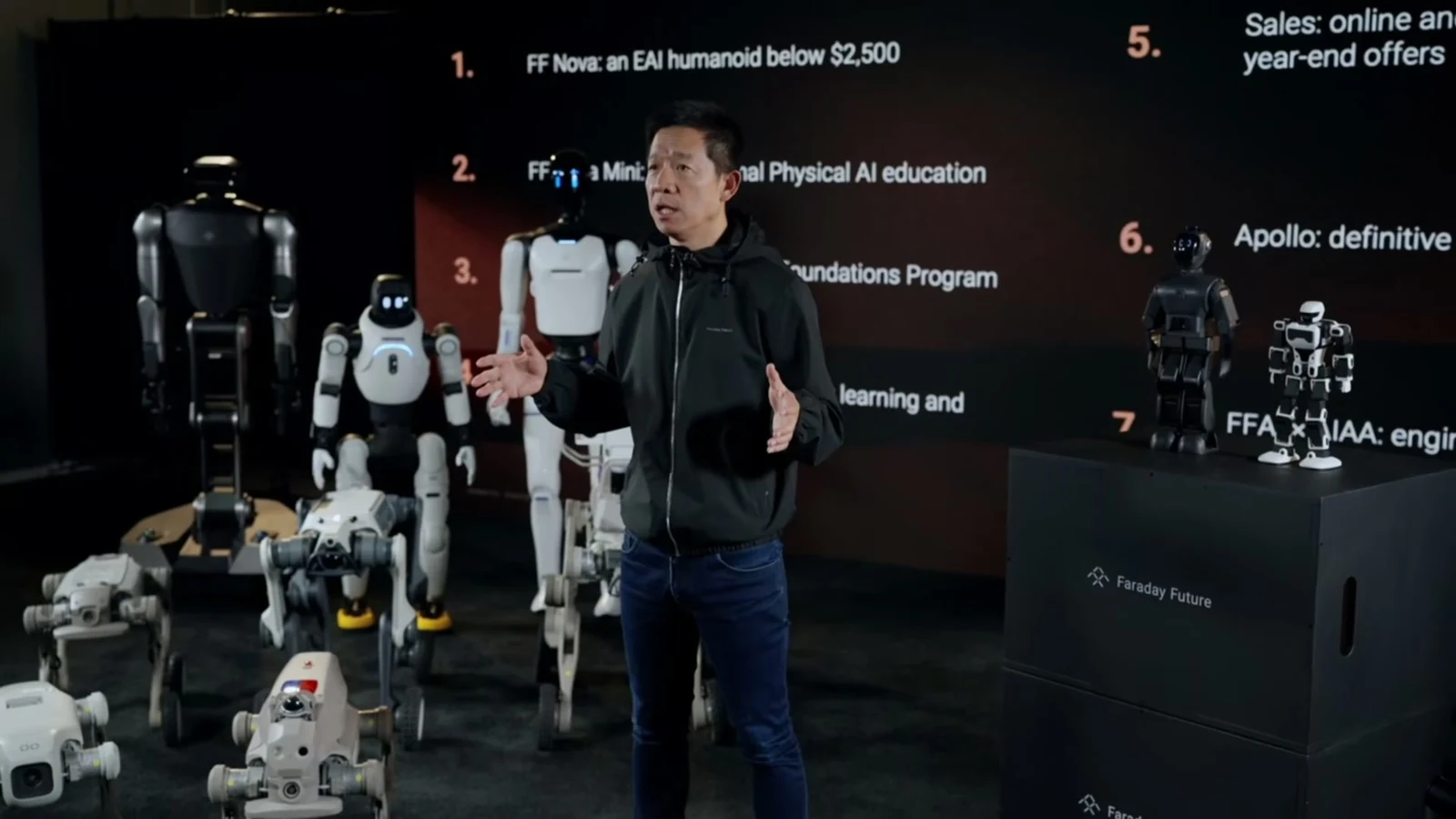 Frame captured at 15:00 from FF’s official joint product-launch recording, showing the presenter and robot lineup, with small robots on the display at right.