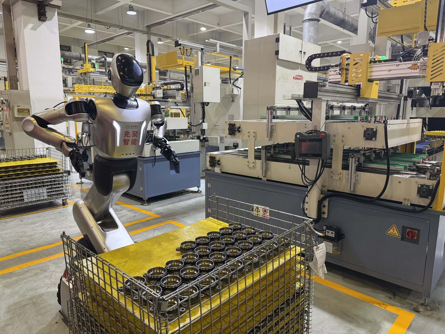 A Leju Kuavo humanoid beside automotive components and production machinery at Zhaofeng.